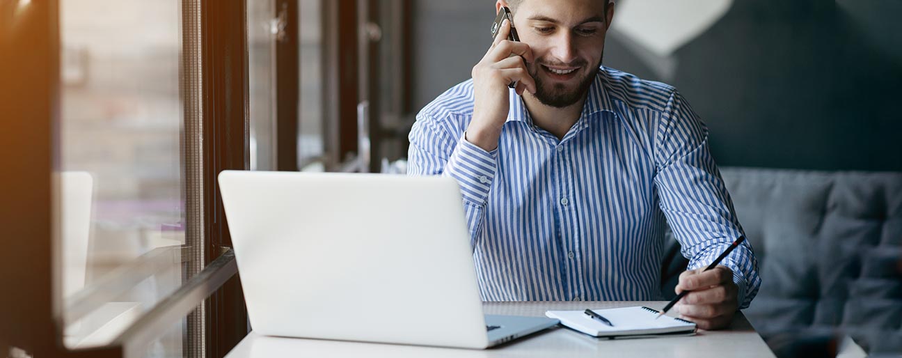 secify-arbete-relefon Man som pratar i telefon framför en dator och papper & penna