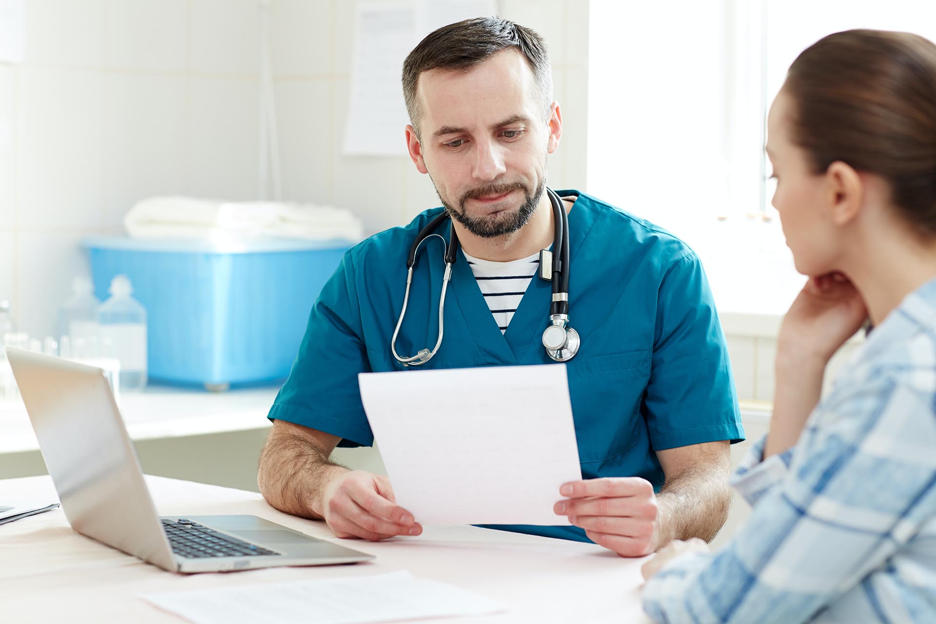 Läkare har ett papper i handen och läser det för en vårdtagare/patient