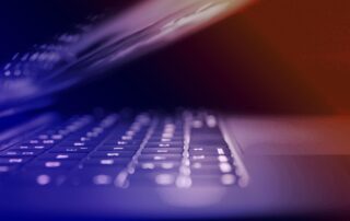 Bild på en bärbar dator som nästan är stängd. Bilden har en ton som går från blått till orange