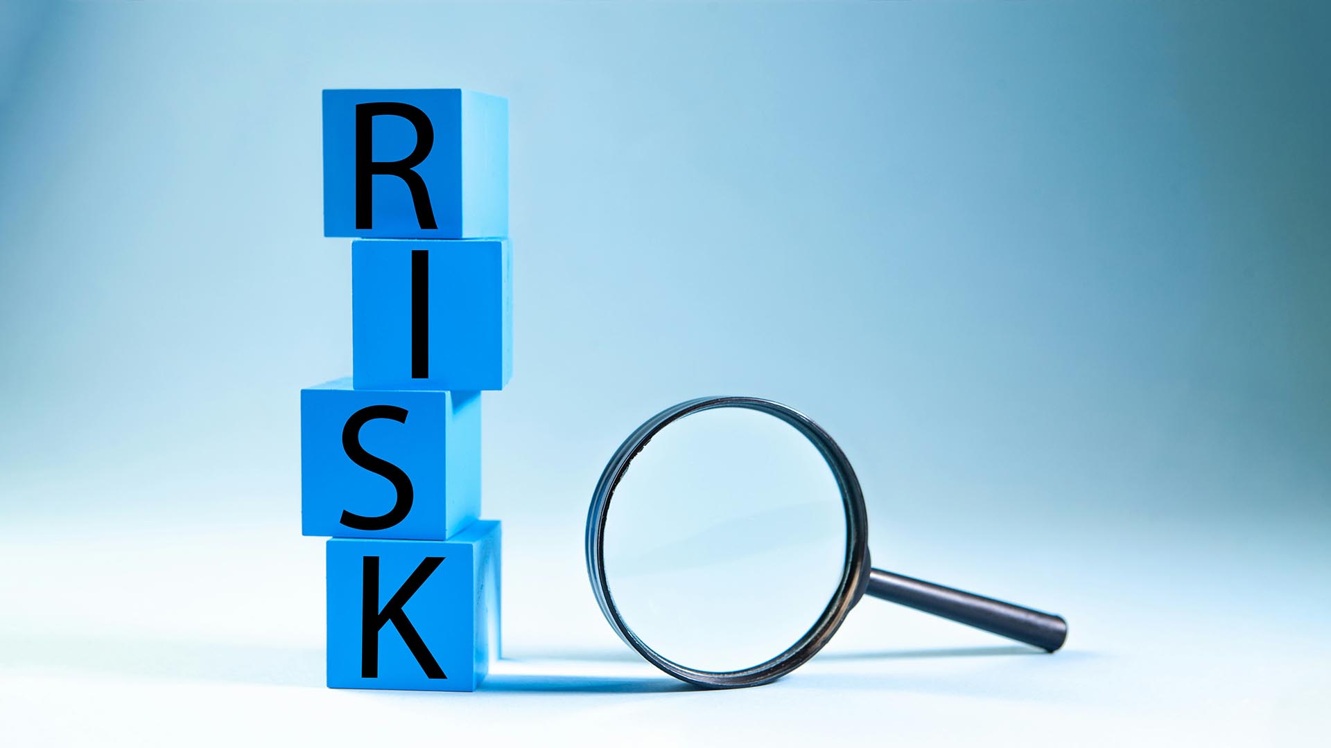 Blå bakgrund med klossar där det står risk, bredvid finns ett förstoringsglas